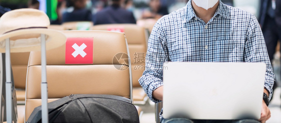 健康座位商业年轻男在机场戴面罩和使用电脑笔记本保护科罗纳感染亚洲男子旅行者坐在新常态轮椅上社会动荡和数字流浪者以及图片