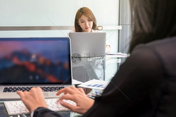 幸福有创造力的在职现代工作场所商业生活方式和技术概念中坐着并使用技术笔记本电脑的亚洲临时穿便衣的青年女商务妇图片