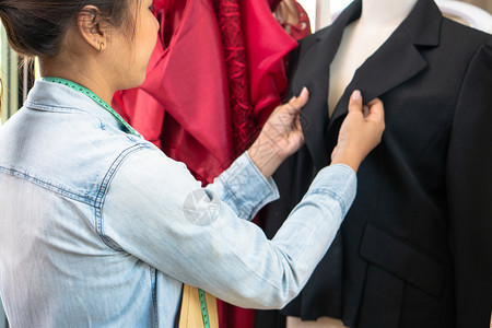 快乐的亚洲年轻女服装设计时师正在检查能否展厅完成一件西装和服这是成功的青年创业者在时装行中的概念措施陈列室在职的图片