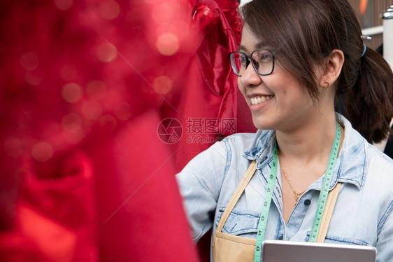 陈列室快乐的亚洲年轻女服装设计时师正在检查能否展厅完成一件西装和服这是成功的青年创业者在时装行中的概念造型师胶带图片