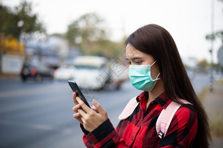 户外使用手机佩戴防护口罩的女性图片