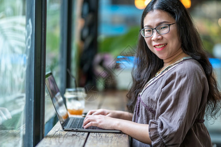 成功愉快在咖啡店用笔记本电脑咖啡杯和智能手机如背景通信概念等工作的女散校对Portnoyunorg专业的图片