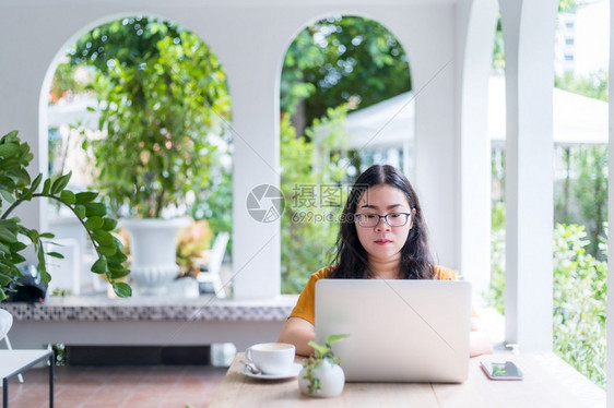 吸引人的白色在咖啡店用笔记本电脑咖啡杯和智能手机如背景通信概念等工作的女散校对Portnoyunorg人们图片