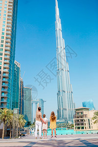 浪漫的城市父亲和孩子家庭在迪拜背景中有摩天大楼从后面的快乐家庭走在迪拜与布吉哈利法摩天大楼在背景中图片