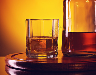 醉威士忌酒杯玻璃和一瓶威士忌黄色背景的威士忌瓶酒精玻璃器皿图片
