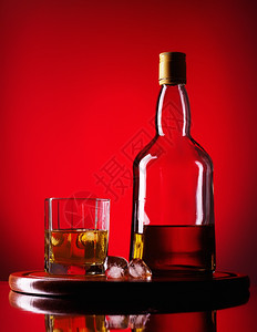 酒精爱尔兰人透明威士忌酒杯玻璃和一瓶威士忌红底的图片