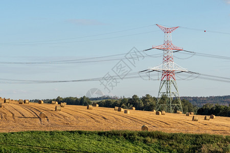 高电压塔附近田地上的草块稻包塔架图片