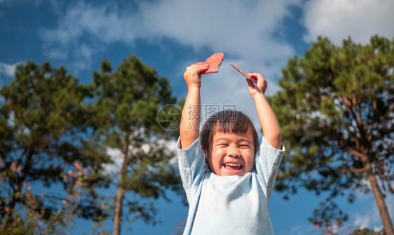 筛选光线穿着两张红心形再生纸板的可爱小女孩在蓝天和绿树背景爱情人节和浪漫概念的象征物上蓝色天空和绿树本健康图片