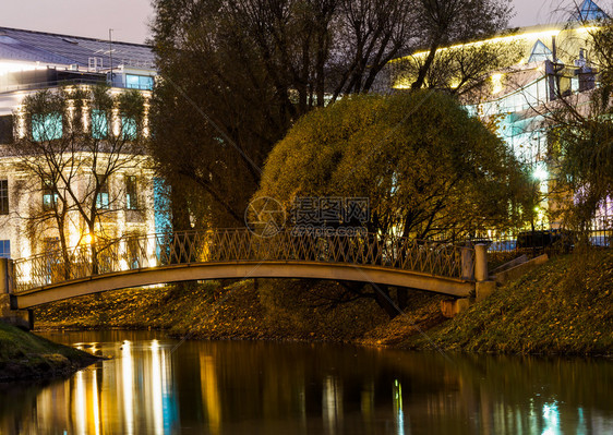 位于现代建筑背景的公园里河上旧桥在现代建筑背景下水小路晚上图片