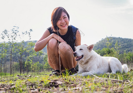 亚洲农村喜欢观赏一位年轻的小阿西娅妇女怀白狗的享受着和平的美景时刻湖边风美丽其背为宠物和女人休息享受生活方式选择焦点等山脉图片