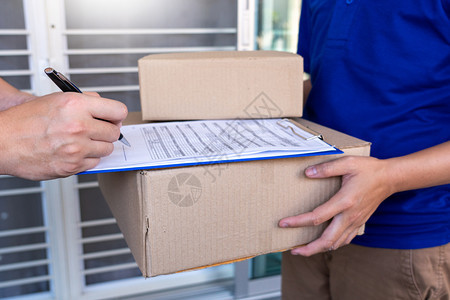 微笑货物工人检查或持有纸板包裹以便向接受交付箱件的客户发送信使货员验收或持有纸板包裹图片