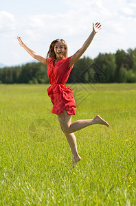 穿红裙子的年轻女孩在森林中游荡于田野夏天美丽的季节图片