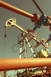 为了石油和天然气行业平台上的油泵钻机操作Pumpjack工业设备油田现场泵正在运行用于发电的摇摆机石油概念调色泵工业设备石油开采图片