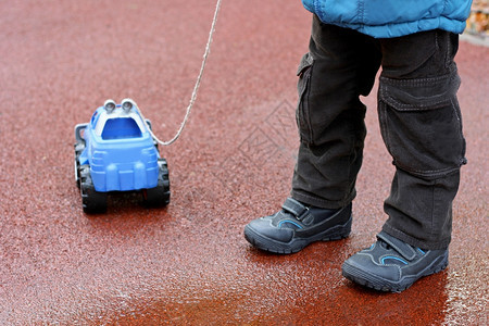 一种身着夹克靴子手套的儿童形象一个在街头的寒冷季节行走玩具车汽拿着绳子照片索图片