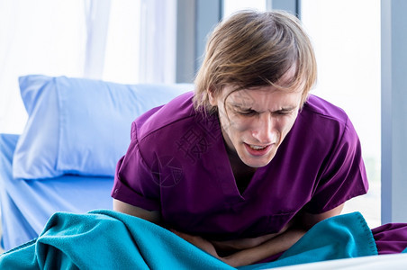肠阑尾炎关心年轻病人患上严重的胃痛躺在床上食物中毒在房间里的病室被毒死在床上图片