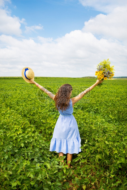 收成俏皮女孩站在田里手拿着一束黄色的花和顶草帽女孩站在田里手拿着一束黄色的花和顶草帽植物图片