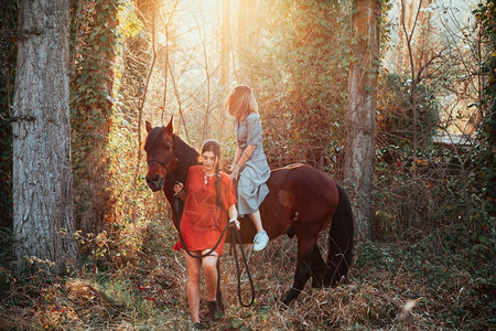 两个女朋友聊天骑着马乘兜风穿过农村的乡间小路他们服用图片