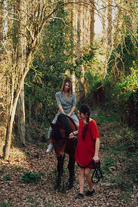 两个女朋友聊天骑着马乘兜风穿过农村的乡间享受朋友们小路图片