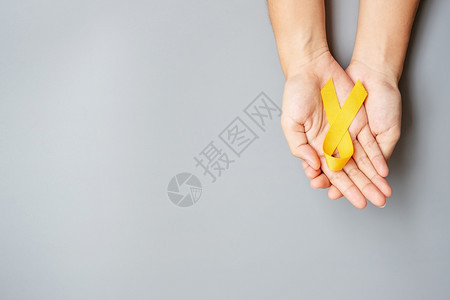 手拿黄丝带预防癌症概念图片