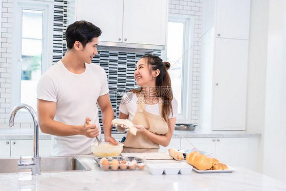 在室内亚洲夫妇一起在厨房做饭和烘烤蛋糕男人和女在家庭爱与幸福概念上互相期待蜜月和情人节主题是甜蜜的月和情人节主题厨师脸图片