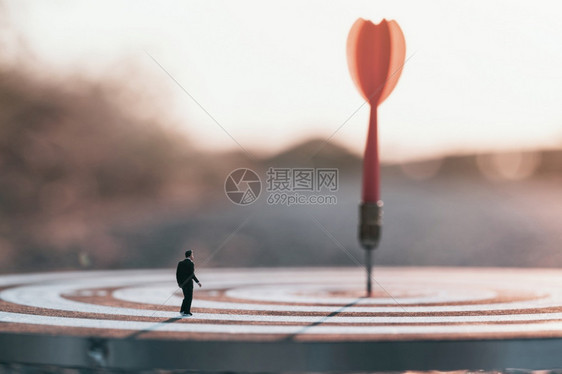 商业想象人在日落背景下站立寻找模糊或失焦的红飞镖箭向目标中心电灯板玩图片