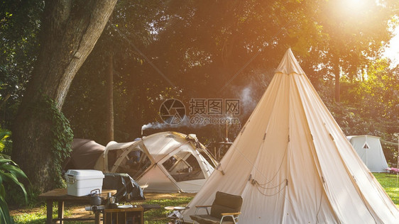 自然公园地带露营区的野帐篷组和配有户外厨房设备的木制桌板露台图片