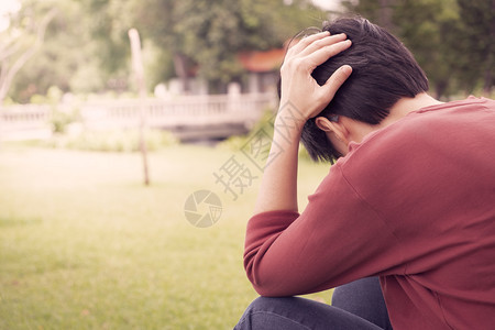 一个人穿红色衬衫用压力抓头在日落的花园里精神健康抑郁症的概念笑声紧张拉年轻的图片