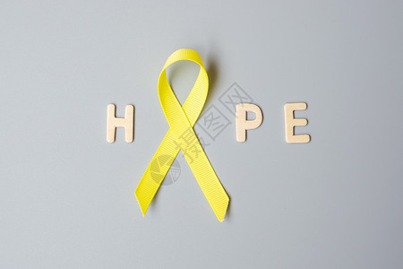 手拿黄色丝带预防癌症概念图片