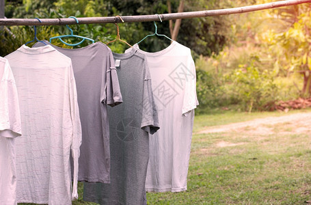 打扫早晨在农舍露户外花园内清洗衣服后挂在木棍上干燥的T恤衫自然图片
