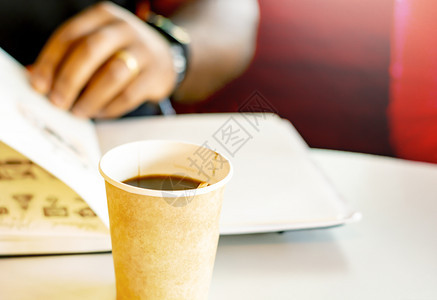 保持白色的教育一杯咖啡个黑人在背面看一本书和咖啡起休息阵子图片