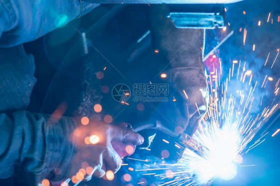 焊机技能在工业作场所与安全钢业合作的焊接工钢铁厂和焊接工钢铁厂一名男子佩戴焊接面罩和保护手套安全防火炬图片
