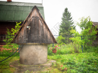 现代简单小屋和后院井的景象从窗户看到雨滴村里老井水灌溉复古的乡村图片