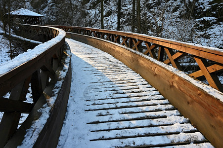 美丽的雪木桥有一条长途徒步的漫道路冬季与雪和太阳一起过冬季节水冰图片
