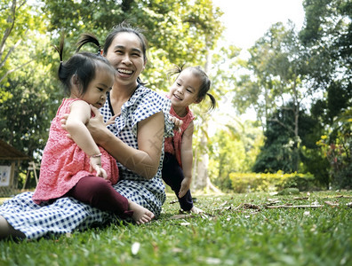 白种人乐趣窥视亚洲母亲和女儿们一起在公园的草地上玩耍如此幸福快乐图片