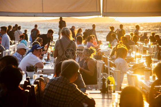 玻璃请享用日落时在海滩边的拥挤餐厅喝图片