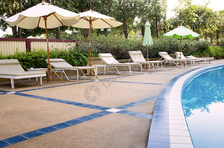 游泳池的海滩椅和雨伞反射采取休闲的图片
