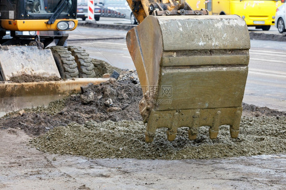 挖土机桶在公路上平均分配混凝土碎石为道路段打下一个地基正在对城市街道CopyspaceCopySproperA路挖土机桶背景的近图片