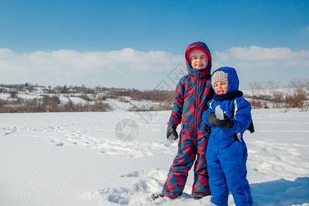 手套雪人欢迎快乐的兄妹在冬季散步公园里玩雪球图片