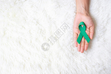 手拿绿色丝带预防癌症概念图片