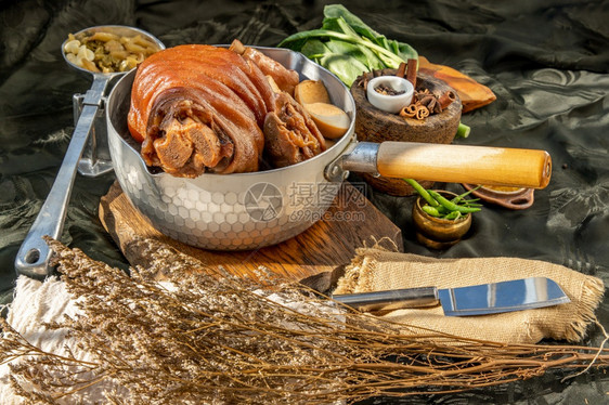 传统菜烤猪腿配有煮熟甜肉汁酱和鸡蛋豆腐甘蓝含瓜菜生和黑底辣椒吃美味的人图片