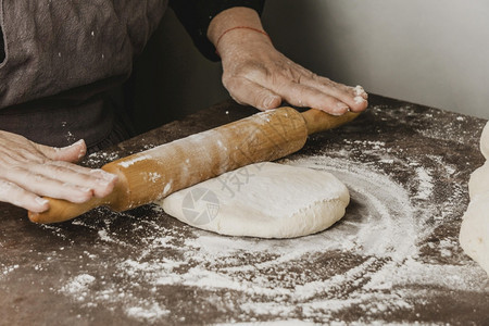 烹饪比萨生长使用滚动针头披萨面团的女厨师使用滚动针头披萨面团的女厨师照片图片