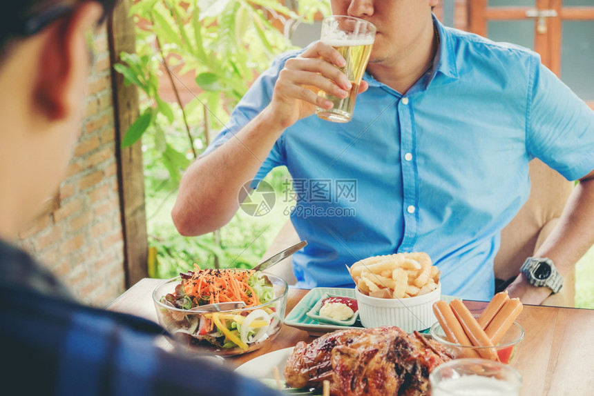 西班牙裔碰杯草案年青的亚洲男人在享受家庭的同时喝着啤酒吃快乐的食物图片