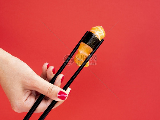 酱苏西筷子Olymupus数字摄影师Camera女人握着竹棍鲑鱼寿司红背景图片
