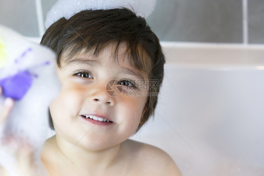 在浴缸里泡了好多快乐可爱的小男孩在浴室里玩泡沫的头部镜儿童保健概念笑声孩子们保健概念孩子保健幸福眼睛洗澡图片