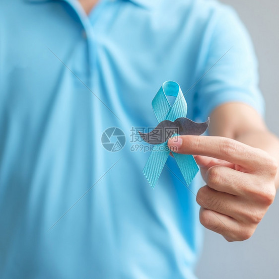 男子拿着蓝丝带预防癌症概念图片