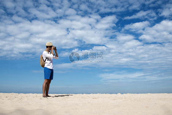 年轻男子在热带海滩上旅行拍照图片