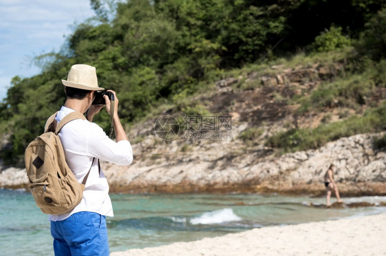 年轻男子在热带海滩上旅行拍照图片