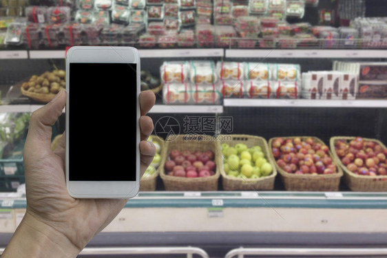 手持智能机在模糊的超市和购物商场零售店上用黑白屏幕遮着智能手机进行产品显示时使用内部背景购物中心走道买图片