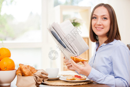 工作照片黑发女商人在家吃早餐时看报纸的照片注按时髦的图片