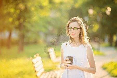 潮人茶女美丽的城市孩肖像手拿着纸杯快乐笑的女人在市公园走着时装金发美女戴着眼镜的美丽金发女孩图片